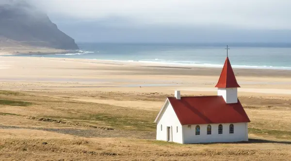 Church, mountains and sand dunes at Breidavik beach